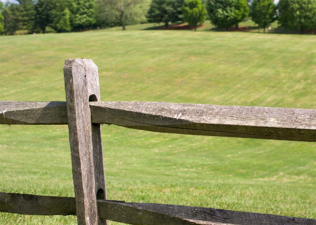 A wooden fence in front of a green grassy area in The Ranch at Lost Creek